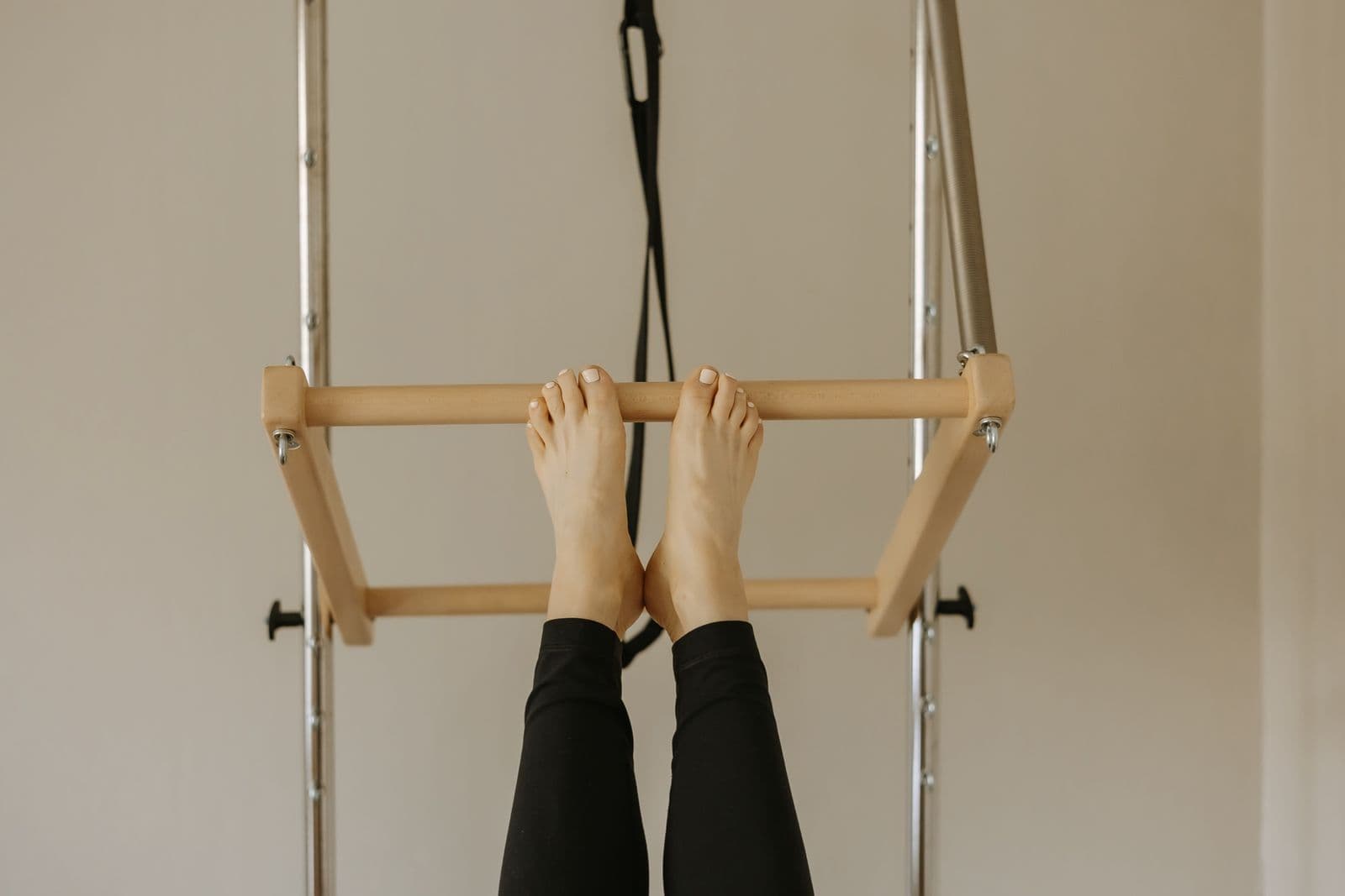 Close-up of feet resting on a wooden Pilates bar