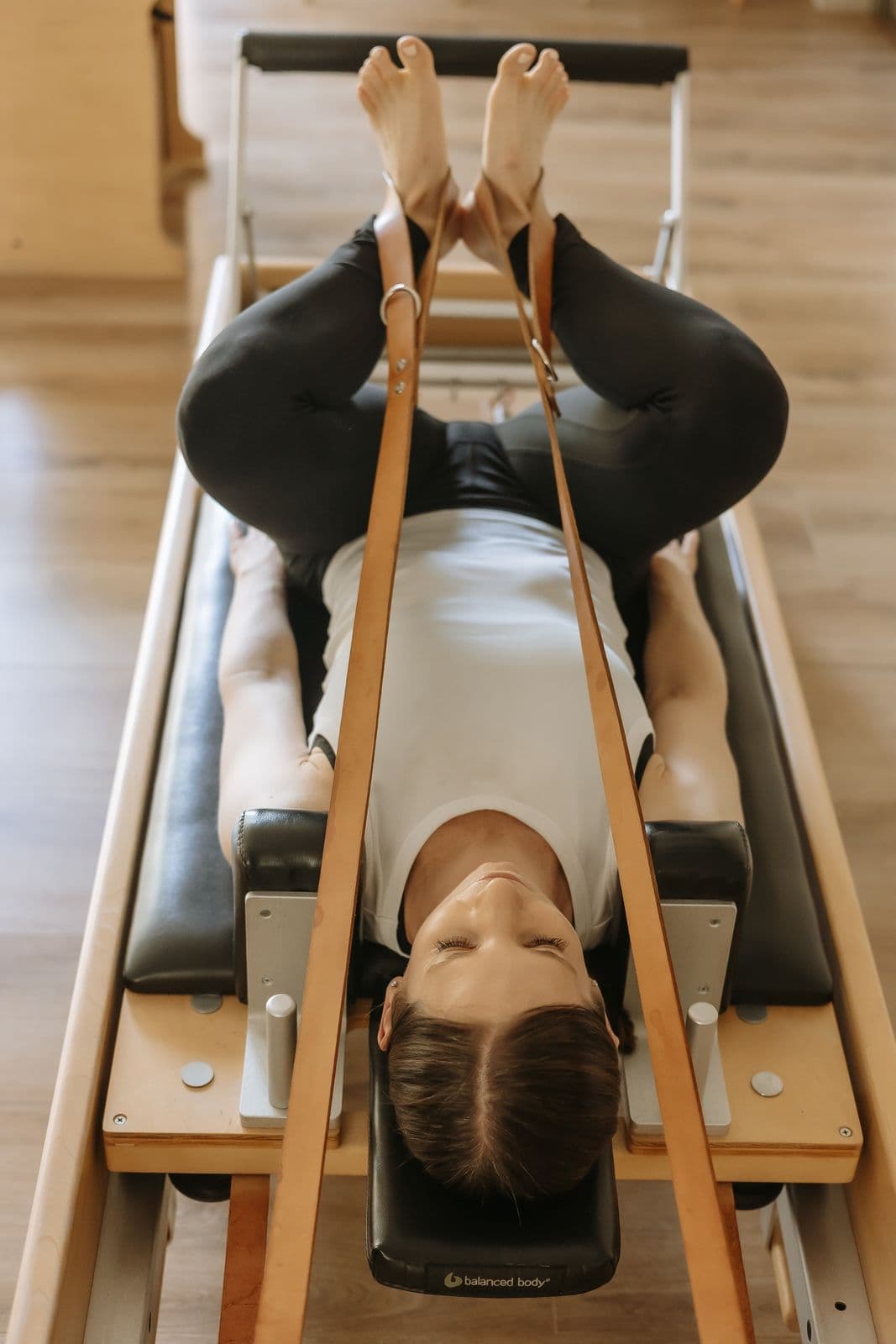 Overhead view of Siân on the reformer, legs lifted in the straps