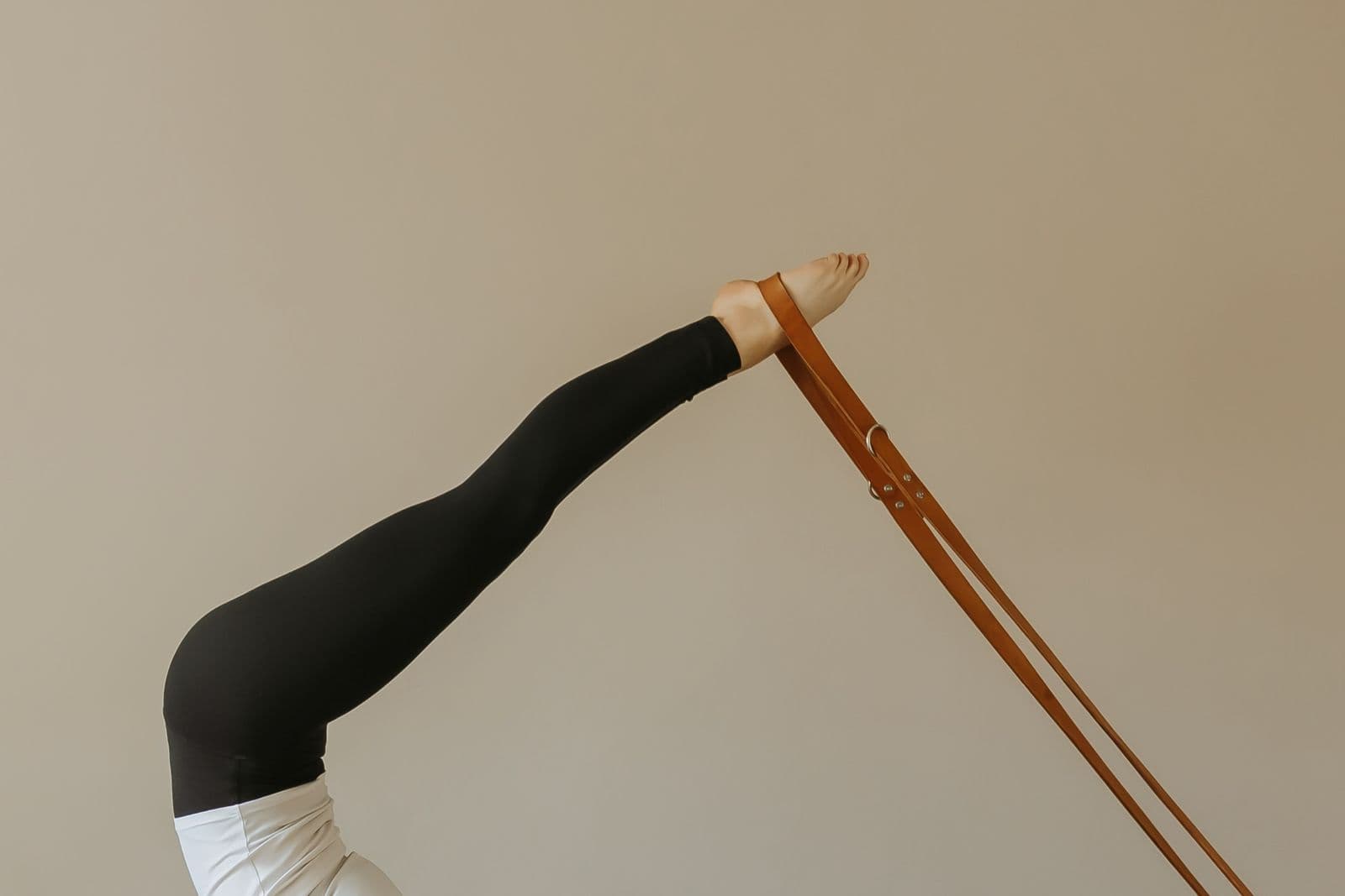 A long, extended leg in a leather strap on the reformer